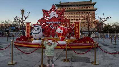 Una niña posa frente a un escenario decorativo de los Juegos en el centro de Pekín