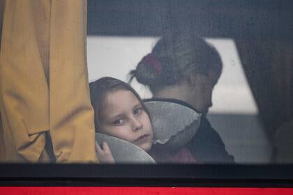 Una niña refugiada que huye de la guerra desde la vecina Ucrania con su familia mira por la ventana de un autobús tras cruzar la frontera en ferry en el paso fronterizo de Isaccea-Orlivka, en Rumanía, el viernes 25 de marzo de 2022.