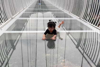 Una niña se arrastra sobre el piso del puente de cristal Bach Long en el distrito de Moc Chau, en la provincia de Son La de Vietnam el 29 de abril de 2022