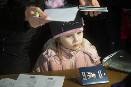 Una niña se para en un escritorio mientras una refugiada ucraniana solicita un permiso de residencia en la sede de la policía extranjera de Praga el 2 de marzo de 2022 en Praga