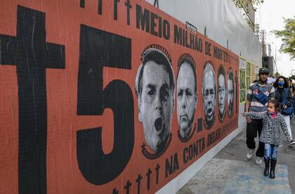 Una niña señala un mural con el rostro del presidente brasileño Jair Bolsonaro durante una protesta por su manejo de la pandemia del COVID-19 en la avenida Paulista, en Sao Paulo, Brasil