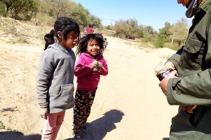 Una niña sonríe al recibir un alfajor. Enfermeros y gendarmes son los únicos que asisten a los habitantes de estos lejanos poblados durante el avance de la pandemia; además, el Ejército tiene una planta de potabilización y distribución de agua en la zona