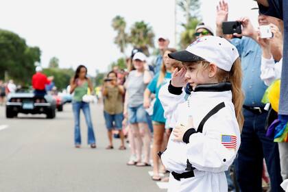 Una niña viste un traje de vuelo saluda mientras observa el desfile de astronautas, en Cocoa Beach, Florida, EE. UU.