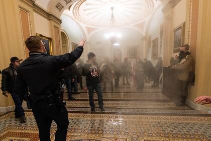 Una nube de humo llena el pasillo frente al Senado durante una confrontación entre policías del Capitolio y simpatizantes del presidente Trump el 6 de enero