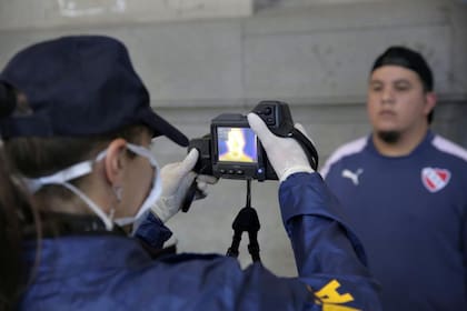 Una oficial de la policía controla con una cámara térmica a un pasajero en Retiro