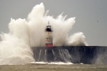 Una ola choca contra un faro en Inglaterra