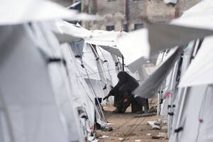 Una palestina desplazada cocina en un campamento adyacente a viviendas y edificios destruidos en Ciudad de Gaza.