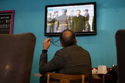 Una pantalla de televisión muestra al presidente chino Xi Jinping asistiendo a una ceremonia oficial de bienvenida a su llegada al aeropuerto gubernamental de Vnukovo-2, a las afueras de Moscú, en una cafetería de San Petersburgo, Rusia, el lunes 20 de marzo de 2023. 