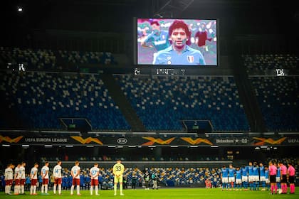 Una pantalla muestra una foto de Diego Maradona, mientras los jugadores guardan un minuto de silencio en homenaje al astro argentino, antes del partido de fútbol del Grupo F de la UEFA Europa League Napoli vs Rijeka, en 2020