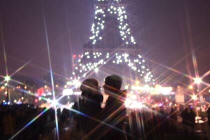 Una pareja celebra el año nuevo en frente de una Torre Effiel iluminada.