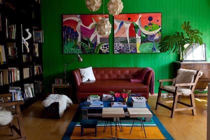 Al entrar a la casa, en la planta baja, aparece el living con la pared de machimbre pintada de verde y dos cuadros de Kalil hechos especialmente para este ambiente. 