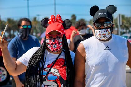 Una pareja espera en la fila para ingresar al centro de Disney en Anaheim, California, el 9 de julio de 2020, el primer día que el complejo de tiendas y restaurantes al aire libre ha estado abierto al público desde que cerró a mediados de marzo en medio de la pandemia de COVID-19.