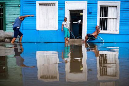 Una pareja permanece fuera de su casa en una zona inundada de Batabanó, Provincia Mayabeque, Cuba, el 28 de agosto de 2023, mientras la Tormenta Tropical Idalia se acerca a la punta occidental de la nación isleña. 