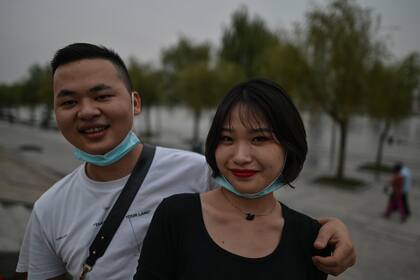 Una pareja que usa tapabocas como medida preventiva contra el coronavirus posa para una foto en un parque junto al río Yangtze en Wuhan, en la provincia central de Hubei en China, el 28 de septiembre de 2020