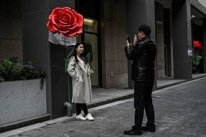 Una pareja se toma fotos junto a una instalación de rosas en el Día de San Valentín afuera de un centro comercial en Pekín, China