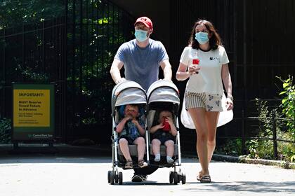 Una pareja usa máscaras protectoras al empujar a los niños en un cochecito mientras la ciudad continúa la Fase 4 de reapertura luego de las restricciones impuestas para frenar la propagación del coronavirus en la ciudad de Nueva York