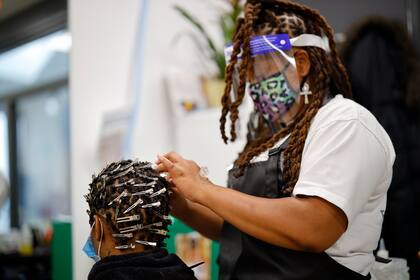 Una peluquera con máscara protectora atiende a una clienta en un salón reabierto en Peckham, sur de Londres, el 4 de julio de 2020