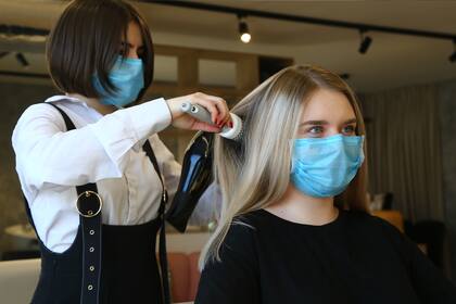Una peluquera y su clienta utilizan barbijos en una peluquería en Vladivostok, Rusia, el 12 de abril de 2020, en medio de la pandemia de coronavirus