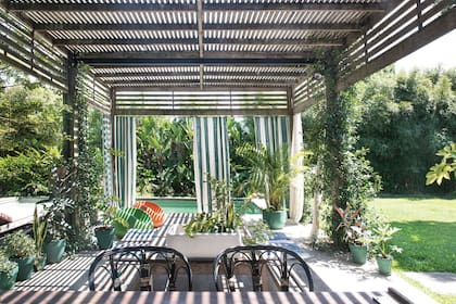 Una pérgola de lapacho con cortinas de lienzo y cenefa de madera.