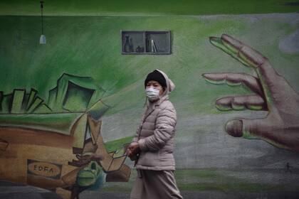 Una persona con barbijo camina por las calles de Wuhan, China