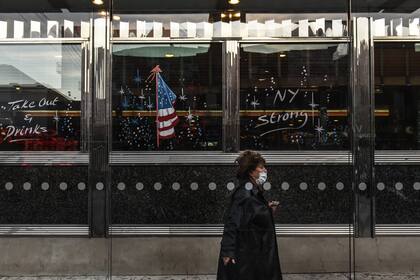 Una persona con mascarilla pasa por el restaurante Bel Aire el 20 de mayo de 2020 en el barrio de Astoria en el distrito de Queens en la ciudad de Nueva York