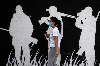 Una persona con tapabocas pasa junto a un mural en la ciudad de Fuenlabrada, en la región de Madrid, que se encuentra bajo bloqueo parcial
