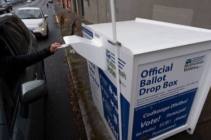 Una persona deposita una boleta en un buzón electoral afuera de las oficina de la División Electoral del condado Multnomah, en Portland, Oregon, el lunes 28 de octubre de 2024. (AP Foto/Jenny Kane)