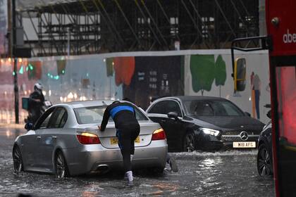 Una persona empuja un automóvil averiado a través de aguas profundas en una carretera inundada en el distrito de The Nine Elms de Londres
