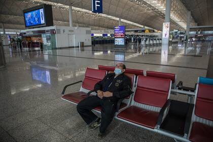 Una persona espera su vuelo en el desierto aeropuerto de Hong Kong; los casos importados y los pacientes asintomáticos generan un rebrote del coronavirus en China