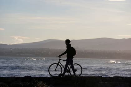Una persona pasa en bicicleta por el Great South Wall en un día soleado de invierno en Dublín, Irlanda