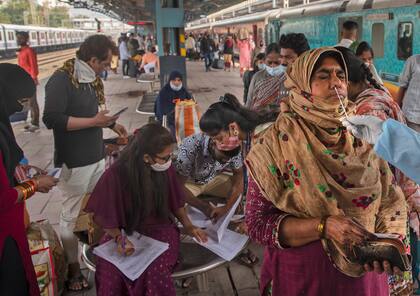 Una persona que trabaja en el sector sanitario usa un hisopo para tomar una muestra de una mujer para realizarle una prueba de COVID-19 en una estación de trenes en Mumbai, India, el jueves 23 de diciembre de 2021. (AP Foto/Rafiq Maqbool)