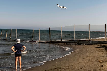 Una persona se para en la orilla del mar mientras un avión desciende hacia el Aeropuerto Internacional de Larnaca de Chipre