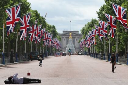 Una persona toma una foto en The Mall mientras las banderas de la Unión ondean para el Jubileo de Platino de la reina Isabel, en Londres, el 26 de mayo de 2022. (Photo by Adrian DENNIS / AFP)