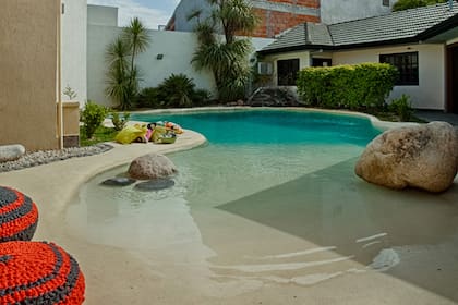 Una pileta recrea un paisaje paradisíaco en el fondo de una casa de Quilmes. Desde la orilla, comienza con un revestimiento arenado antideslizante y suave que representa la playa. La ilusión se completa con piedras grandes y pequeñas.