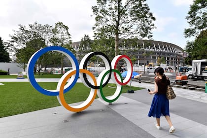 Una postal de los anillos de los Juegos Olímpicos. De fondo, el nuevo estadio Nacional de Tokio