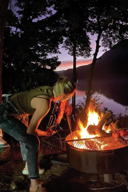 Una postal de Vicky cocinando al aire libre con leña durante una viaje a Bariloche.