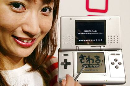 Una promotora presenta la consola Nintendo DS en 2004. El dispositivo de la compañía japonesa presentará una pantalla 3D que no requerirá anteojos especiales