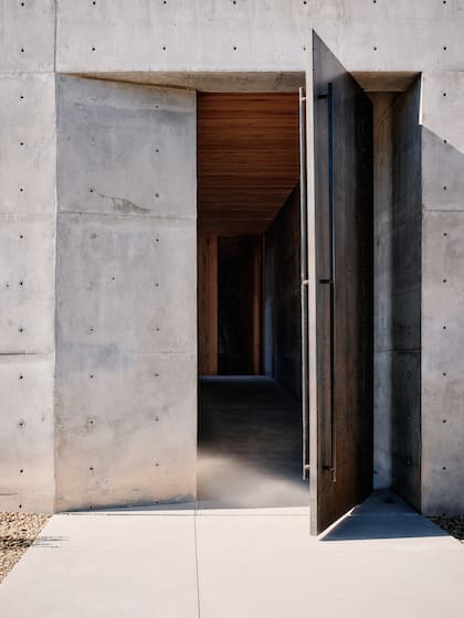 Una puerta monumental que anticipa la sobriedad y la fuerza del concreto en el interior.