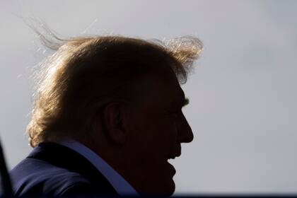 Una ráfaga de viento atrapa el cabello del expresidente Donald Trump mientras se quita brevemente su gorra roja