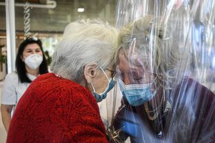 Una residente del asilo de ancianos Domenico Sartor en Castelfranco Veneto, cerca de Venecia, abraza a su hija el 11 de noviembre de 2020 a través de una pantalla de plástico en una llamada "Sala de Abrazo" en medio de la pandemia de coronavirus