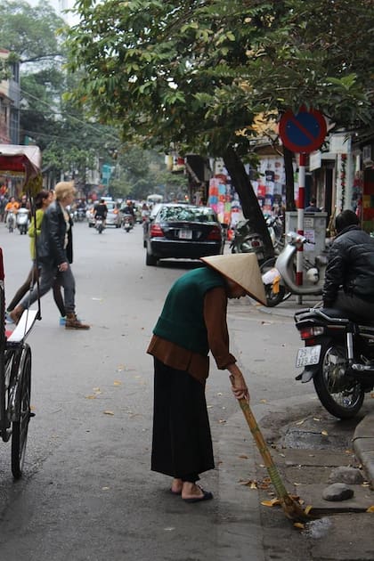Una señora barre las calles en Hanoi