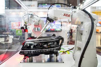 Una serie de brazos robóticos en exposición ponen a prueba los faros de un vehículo en una exposición de robots industriales en Brno, la segunda ciudad más grande de República Checa