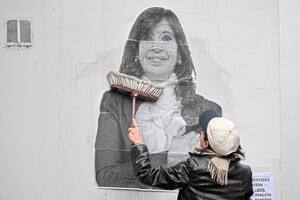 Una simpatizante de la expresidenta argentina Cristina Fernández de Kirchner pega un cartel frente a su residencia en Constitución