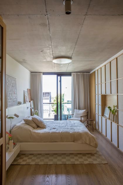 Una sola pieza lacada integra el respaldo de cama y las mesas de luz.