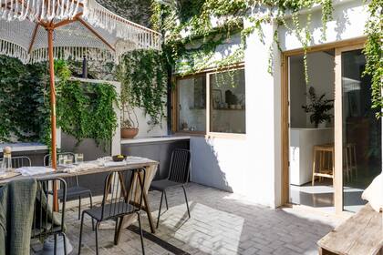 Una sombrilla tejida por la madre de Agustín protege la mesa sobre caballetes. Sillas (Estudio Te) con mantas (Lote Propio). Jarras y vasos (Philippa Deco Boutique).