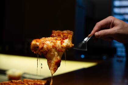 Una tentadora pizza que rebalsa de muzarella.