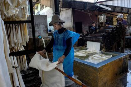 Una trabajadora cuelga láminas de caucho natural en la cooperativa de caucho Klongpan en la provincia de Trang