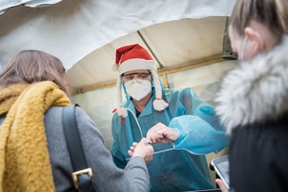 Una trabajadora de la salud con un sombrero de Navidad toma muestras de hisopado fuera del club nocturno Berlin KitKatClub, convertido en un centro de pruebas de coronavirus, el 23 de diciembre de 2020 en Berlín