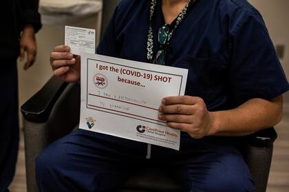 Una trabajadora de la salud sostiene un letrero que muestra los motivos personales para vacunarse después de recibir una de las primeras dosis de la vacuna de Moderna, en el Christ Hospital en Jersey City, Nueva Jersey, el 21 de diciembre de 2020