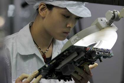 Una trabajadora examina una placa madre en la línea de producción de Foxconn, una de las principales proveedoras de Apple
